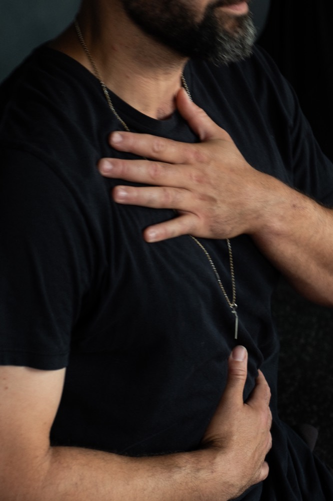A participant with one hand on their chest and one hand on their belly, tracking breath mechanics