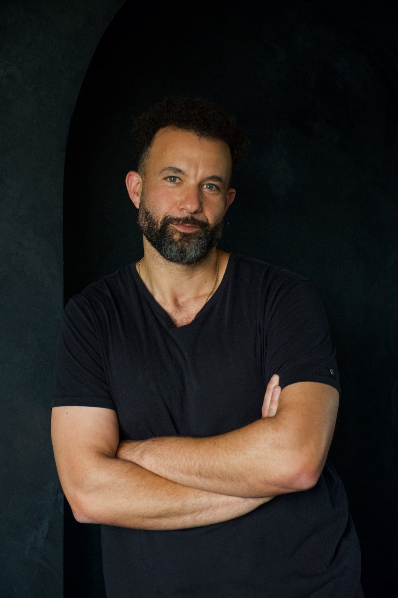 Tarik Hassan, co-founder of State Shift Studios, arms crossed, in a black tee